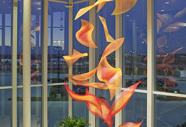 Sunrise Cascade suspended contemporary sculpture by Talley Fisher in a glass atrium at dusk.