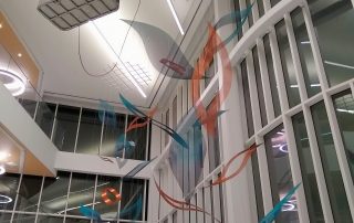An art rigger in an aerial lift installs cables to a grid suspending the atrium sculpture.