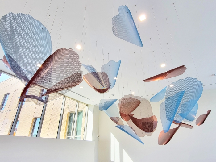 Blue and copper petals are suspended from the lobby ceiling in groups that resemble blooming flowers.
