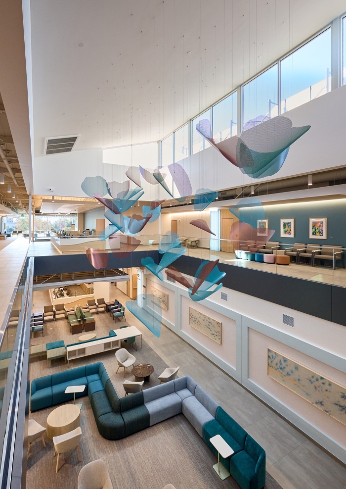 Blue and copper poppy blooms are suspended in the atrium of a healthcare facility.